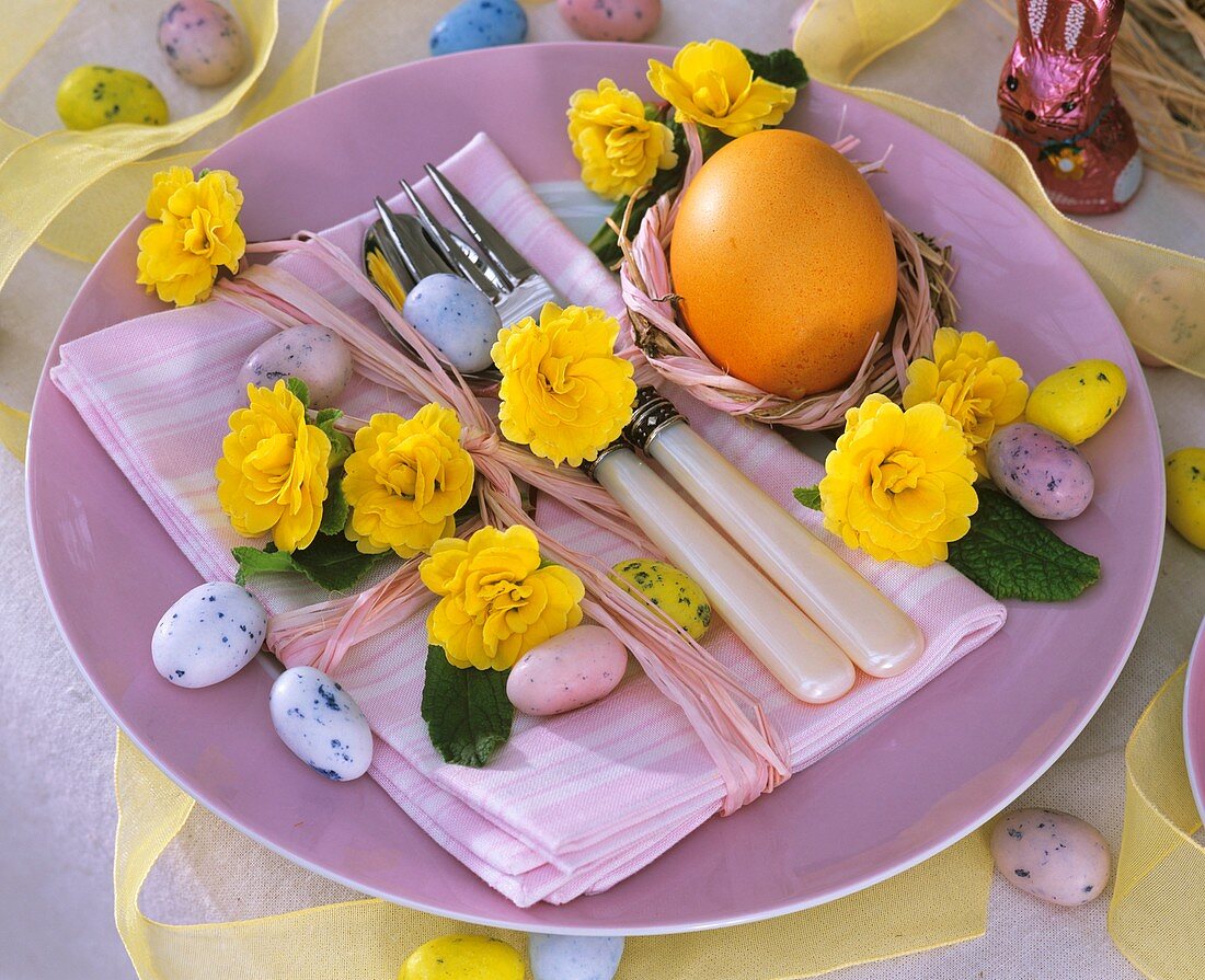 Ostergedeck mit Primelblüten, Ei und Zuckereiern