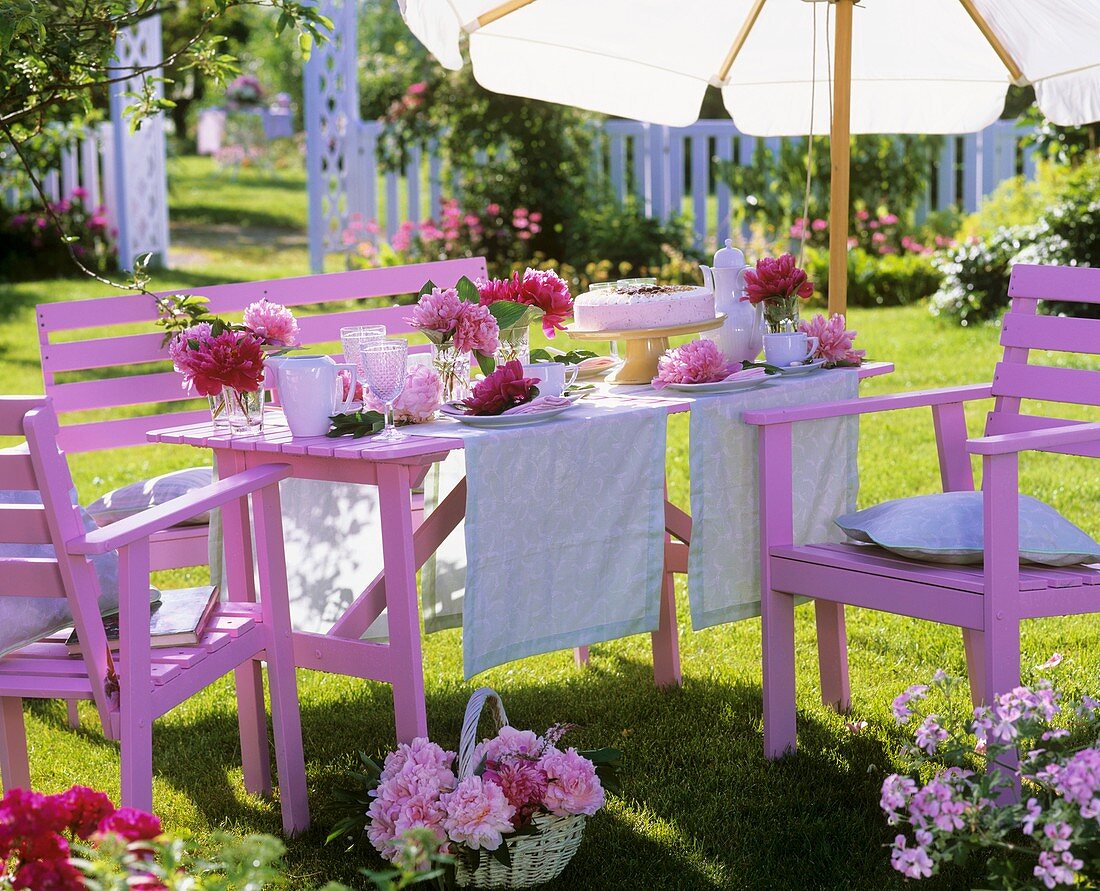 Gedeckter Tisch mit Pfingstrosen und Torte im Garten