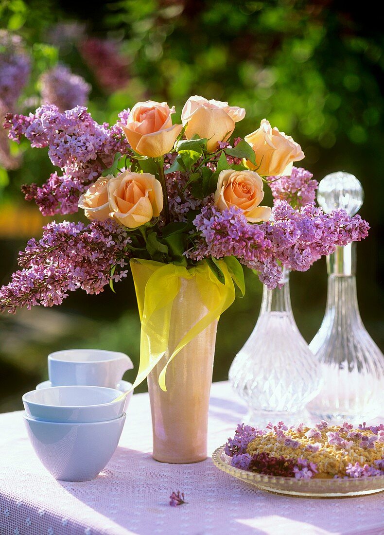 Tisch mit Streuselkuchen und Flieder-Rosen-Strauss im Freien