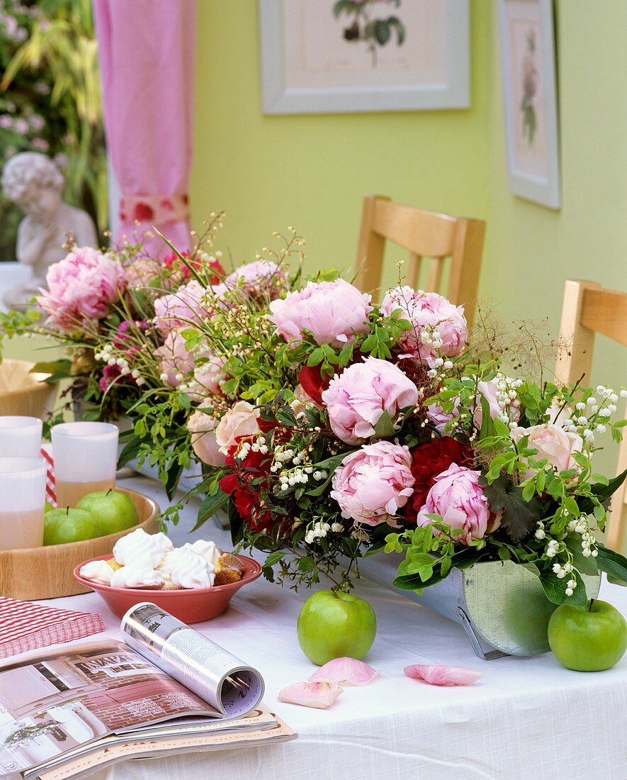 Peonies, lilies-of-the-valley, meringues, juice & apples on table