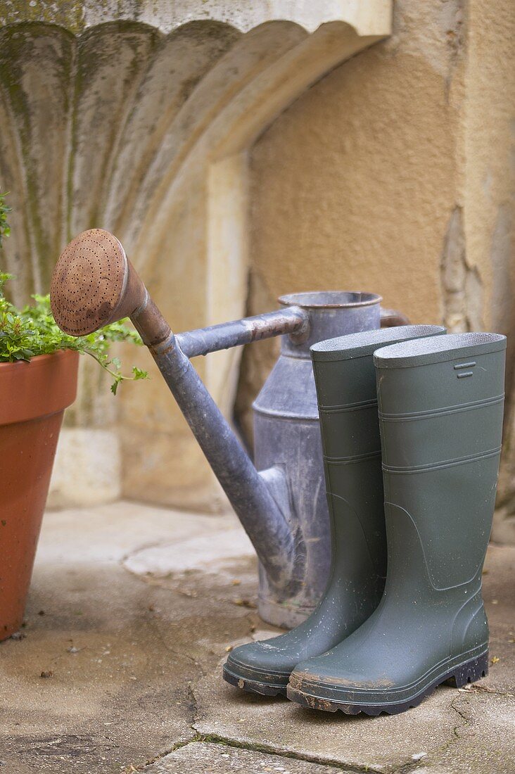 Rubber boots and watering can in front of garden tap