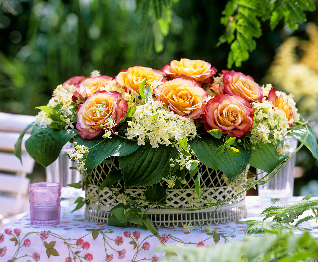 Drahtkorb mit Rosenblüten, Hortensien, Clematisranke