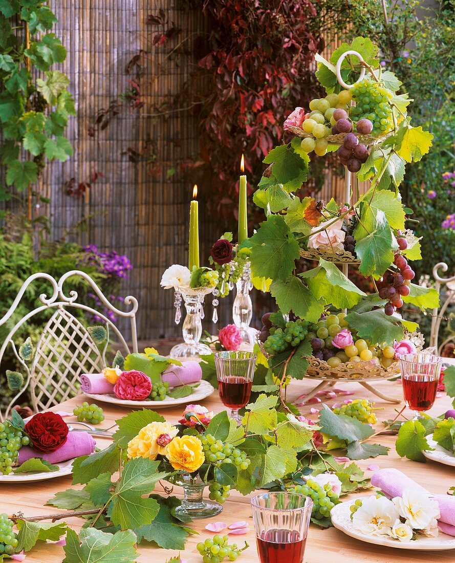 Weiße, gelbe, rosa und rote Rosen mit Trauben als Tischdeko