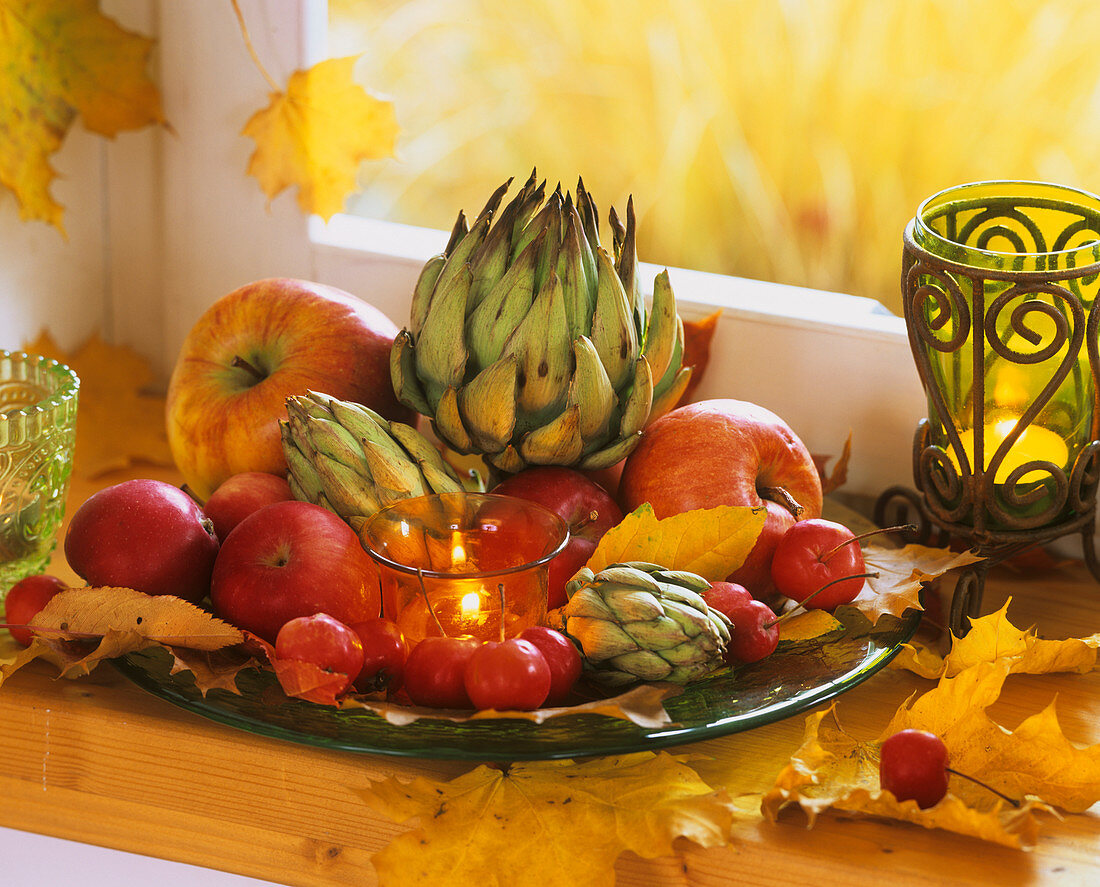 Deko mit Herbstlaub, Artischocken und Äpfeln und Zieräpfeln