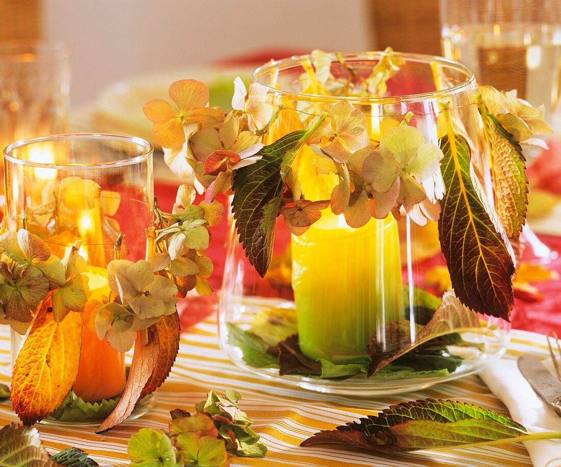 Candles in glasses decorated with flowers and leaves