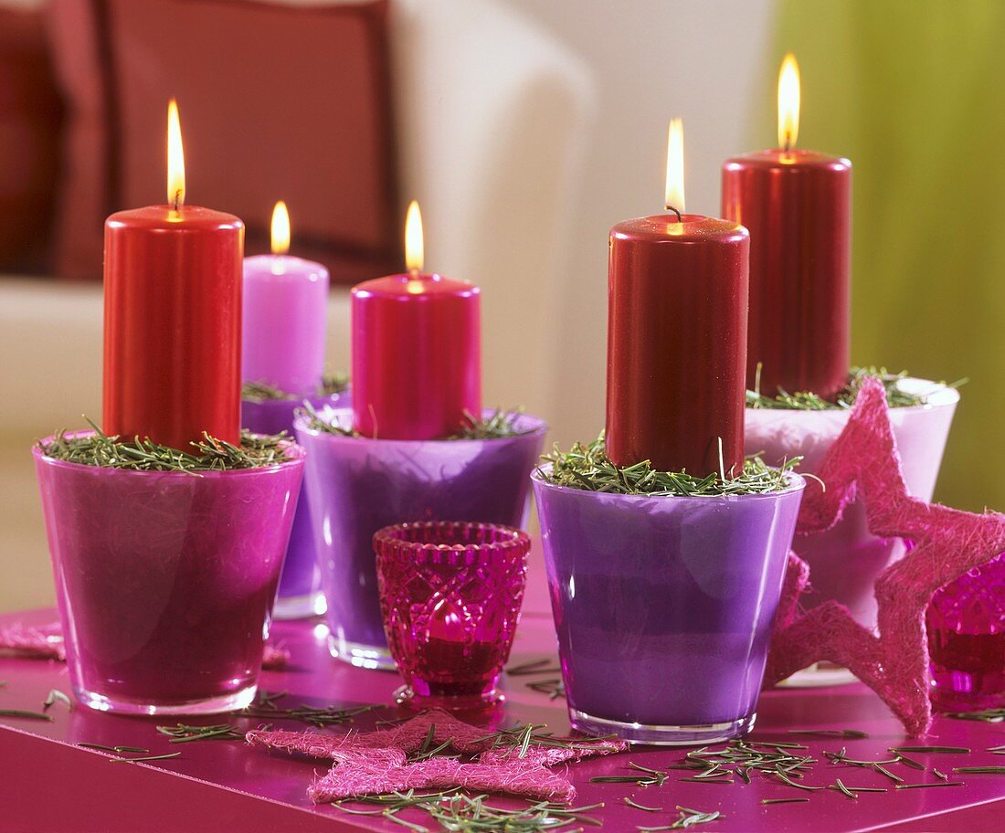 Kerzen mit Tannennadeln in pink und lila Gläsern
