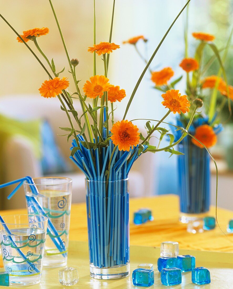 Ringelblumen & Goldleistengras in blauen Strohalmen steckend