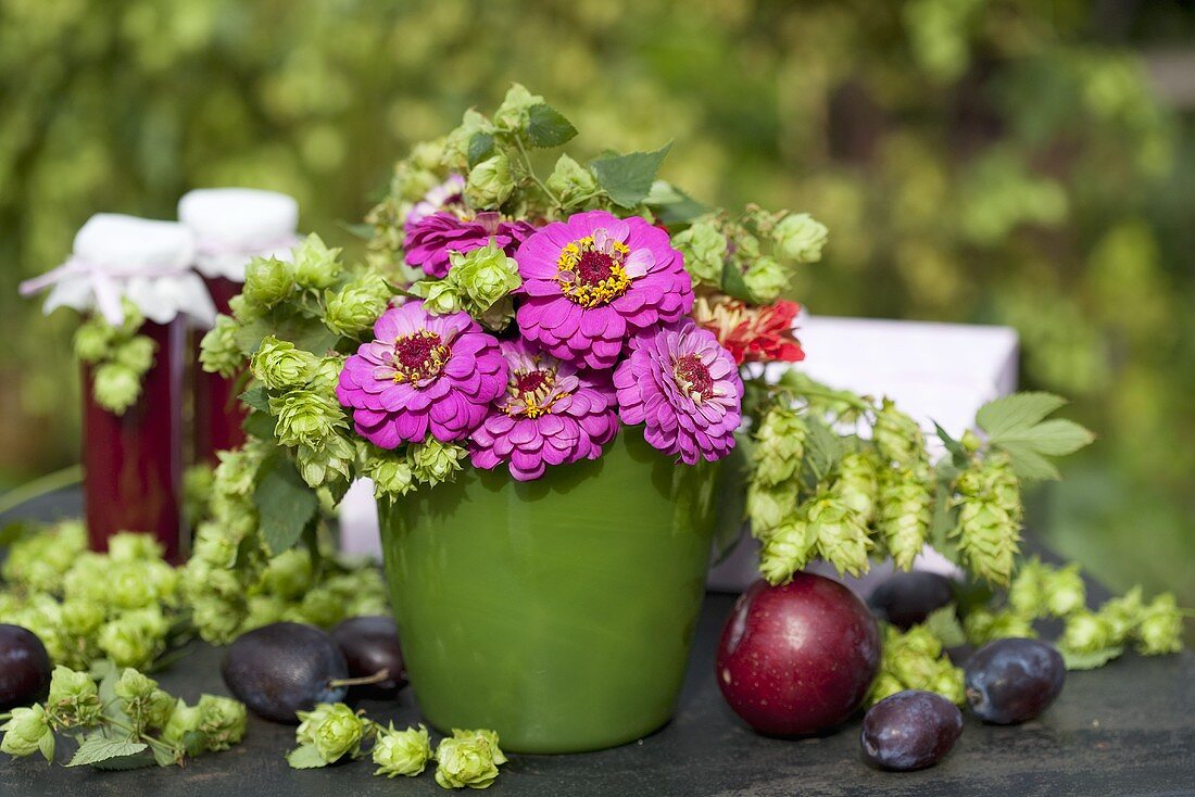Vase of pompom dahlias and hops, plums, jam