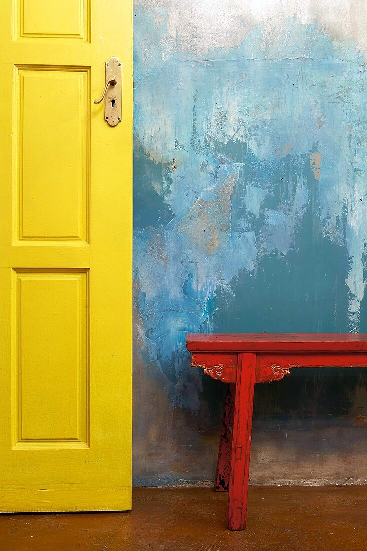 A patchy blue wall with yellow door