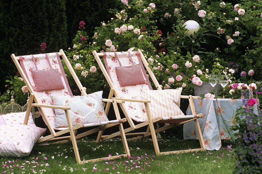 Two deckchairs with cushions in a rose garden