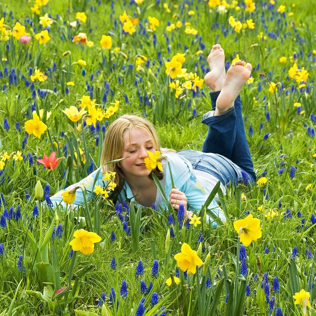 Mädchen auf Frühlingswiese mit Narzissen und Traubenhyzinthen