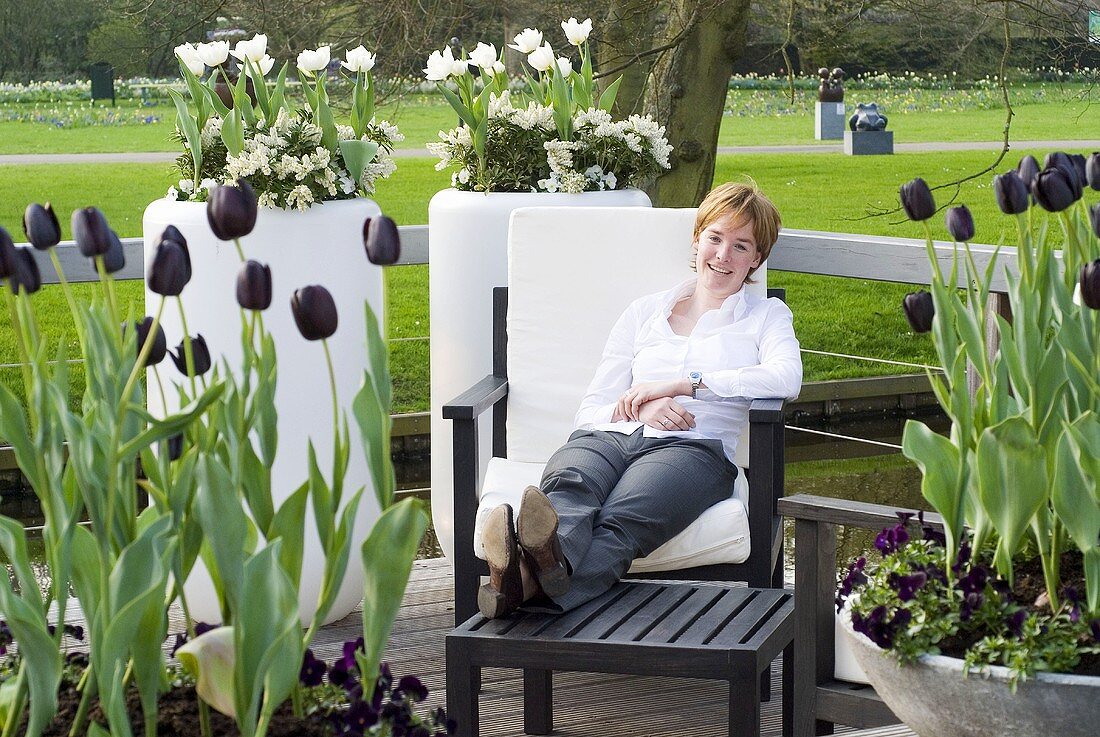 Woman on garden chair among pots of tulips