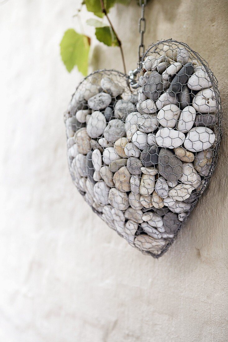 Wire heart filled with pebbles on wall