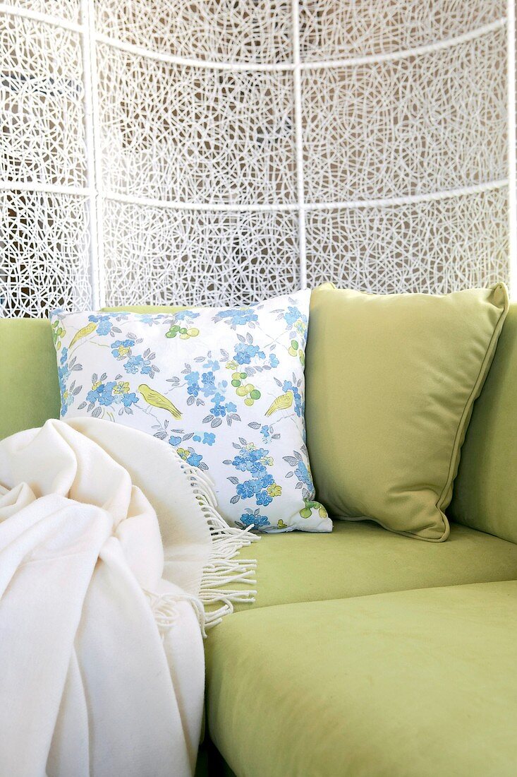 Lindgrünes Sofa mit Kissen und Decke
