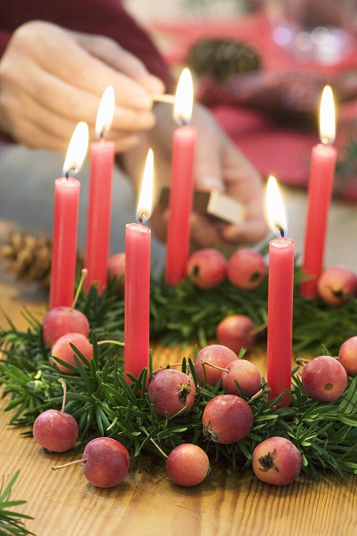 Kerzen werden am Weihnachtskranz angezündet