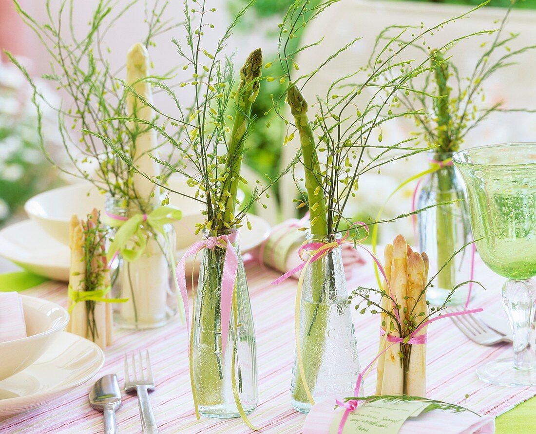 Weisser & grüner Spargel in Glasflaschen auf gedecktem Tisch