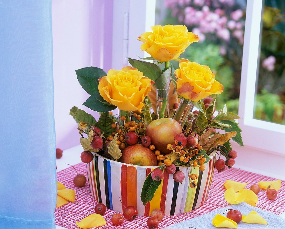 Gesteck aus gelben Rosen, Zieräpfeln, Äpfeln und Herbstlaub