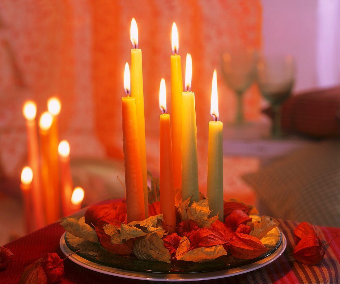 Kerzen auf Glasteller mit Lampionblumen und Herbstlaub