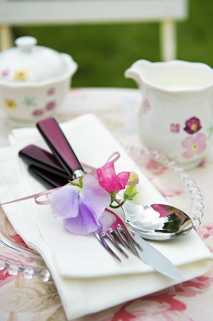 Gedeck mit Blumendeko auf Gartentisch