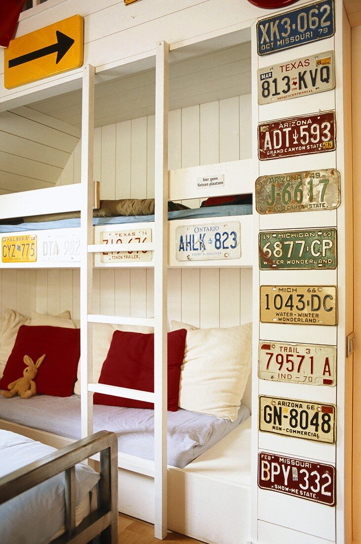 Schlafraum mit eingebautem Stockbett und aufgehängter Autokennzeichen-Sammlung