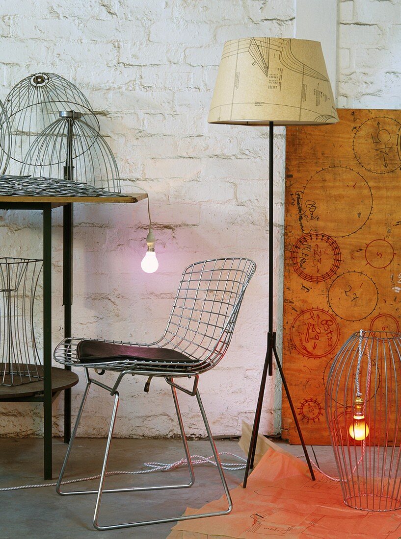 Classic wire chair and 50s-style standard lamp surrounded by lampshade frames in artistic lighting workshop