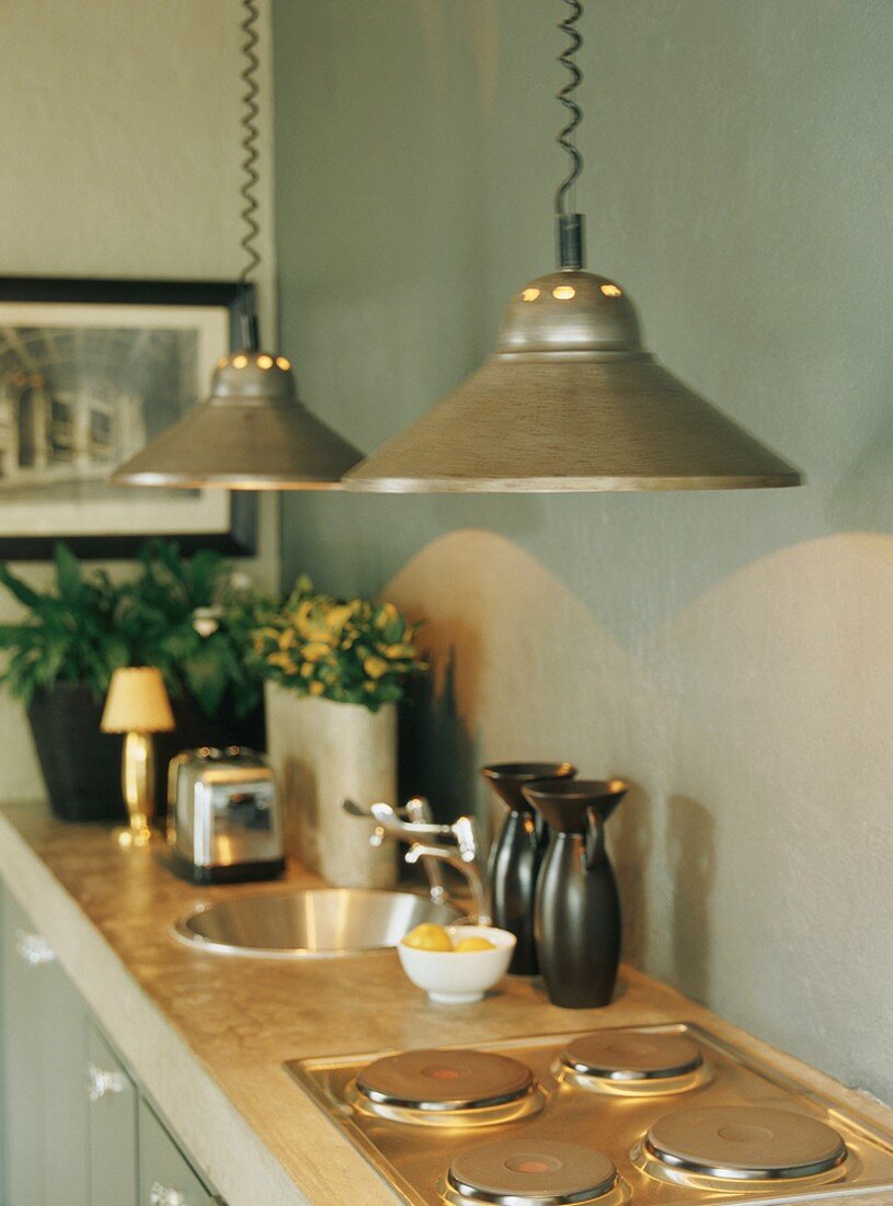 Küchenzeile mit Hängeleuchten über Herdplatten und runder Spüle in Beton-Arbeitsplatte