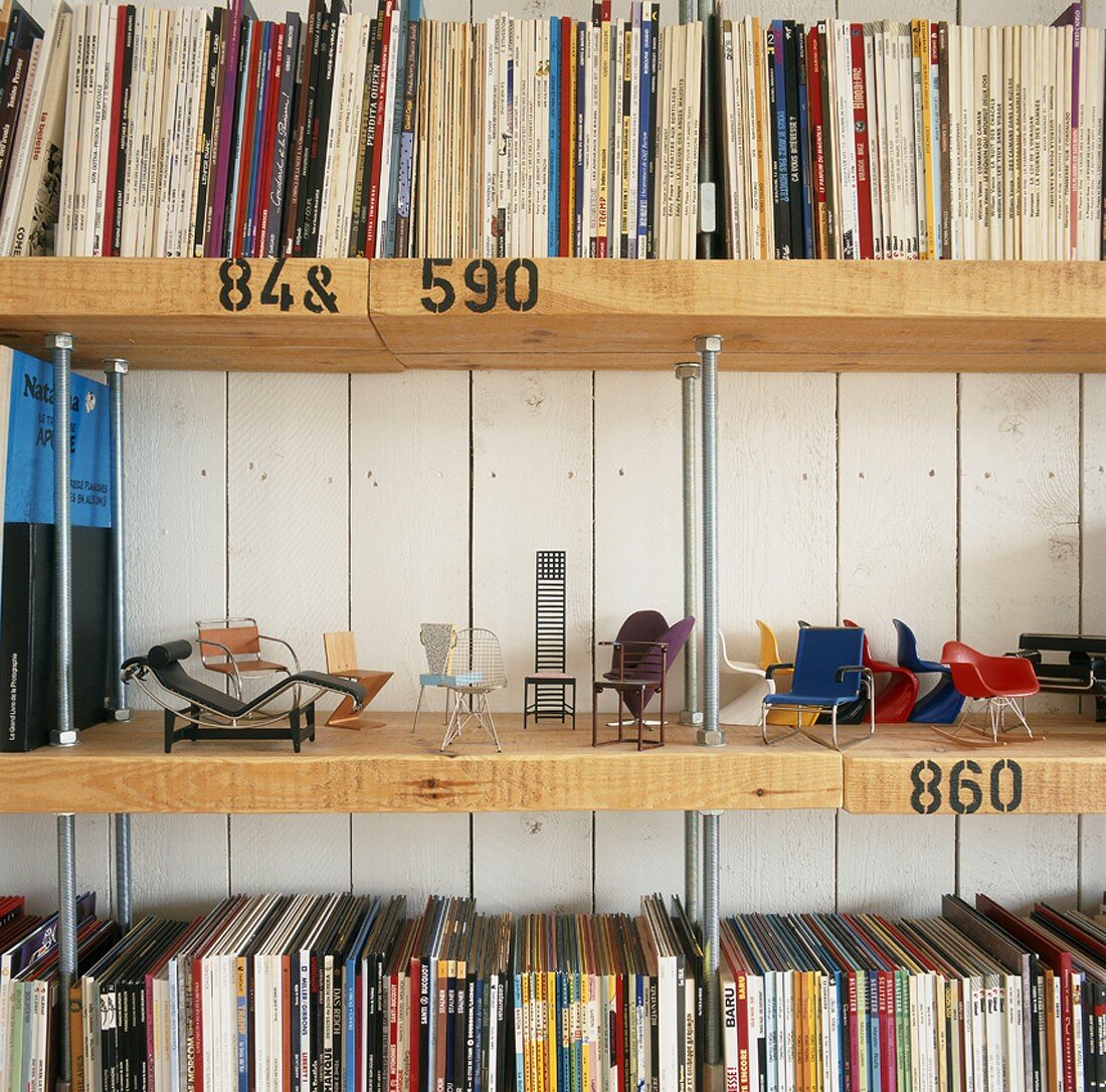 Ausschnitt eines selbstgebauten Bücherregals mit Modellen von klassischen Designer Sitzmöbeln
