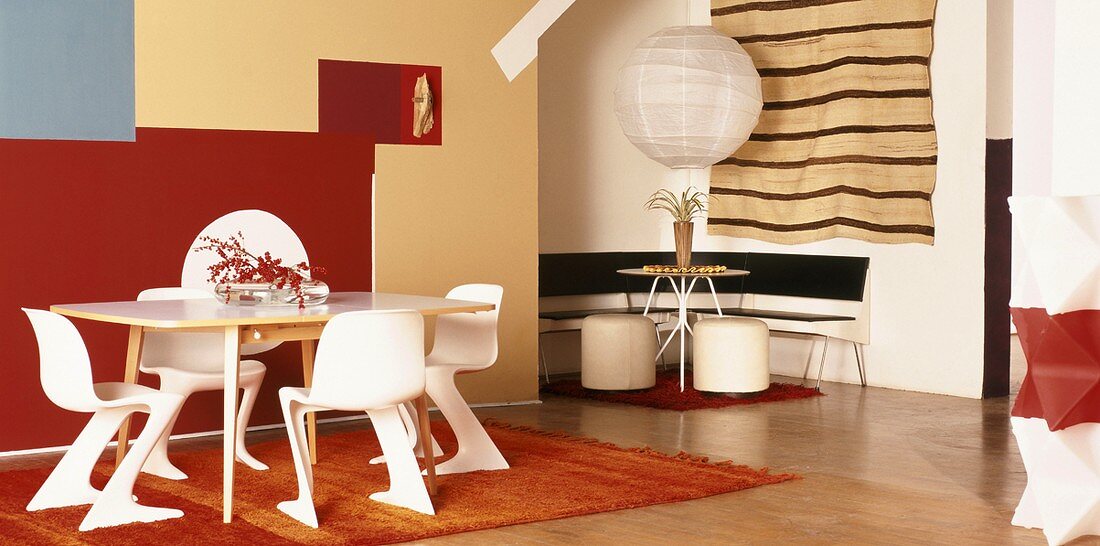 Tische und Stühle in Weiß vor künstlerischer, farbiger Wandgestaltung