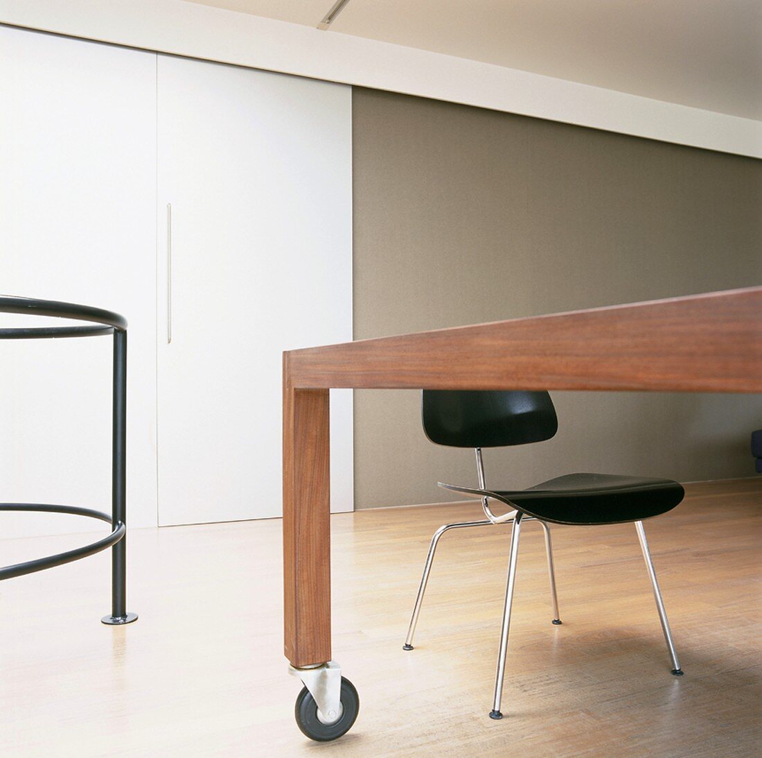 Schwarzer Stuhl mit Stahlrohrgestell an modernem Holztisch mit Rollen