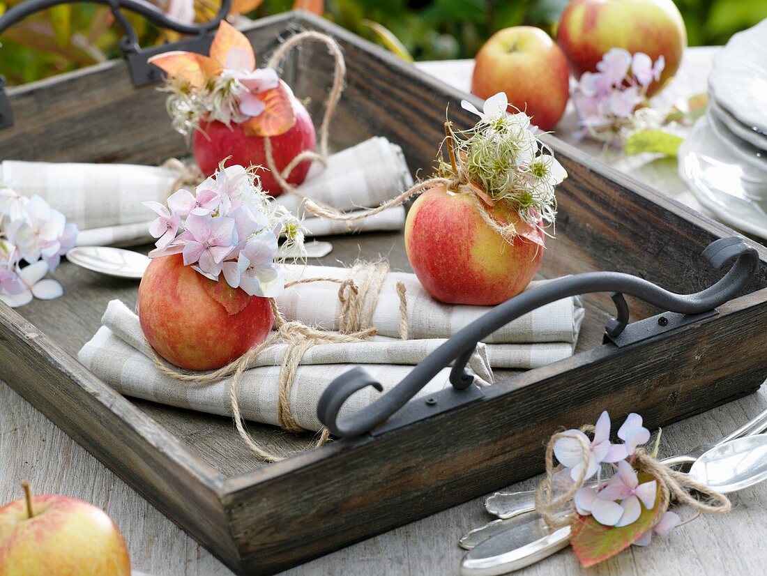 Äpfel mit Hortensienblüten, Clematis und Herbstlaub als Serviettendeko