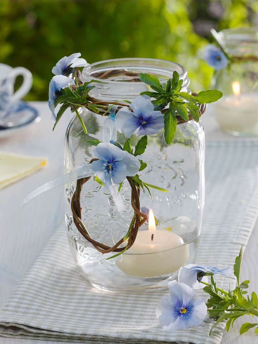 Kerze im Glas mit Weidenkränzchen und Hornveilchen