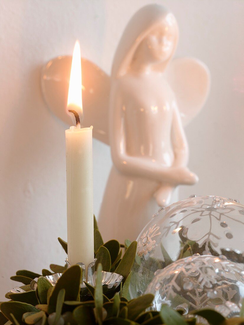 White candle in front of porcelain angel