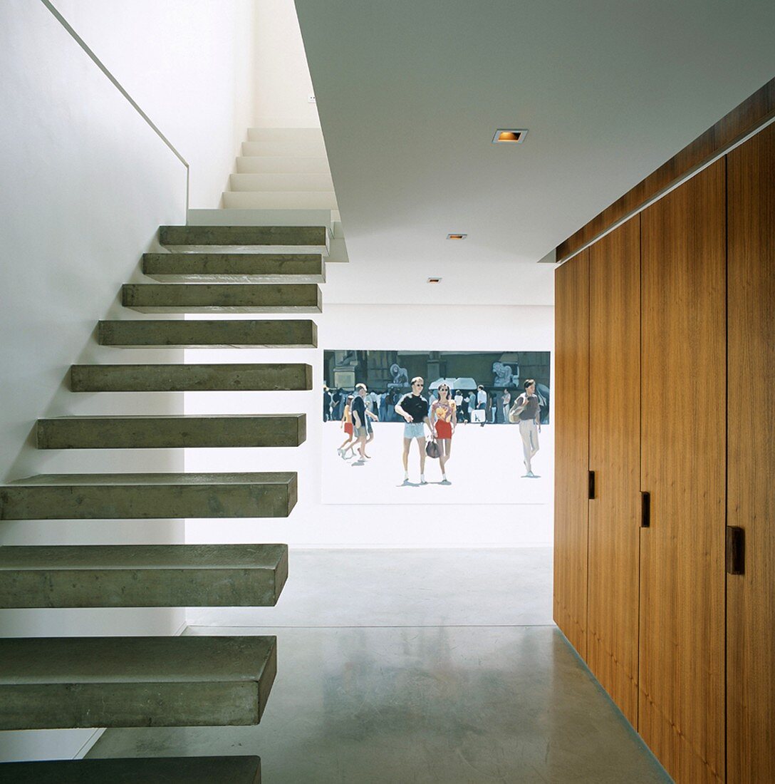 Minimalist staircase with cantilever concrete treads and photo projected onto hall wall