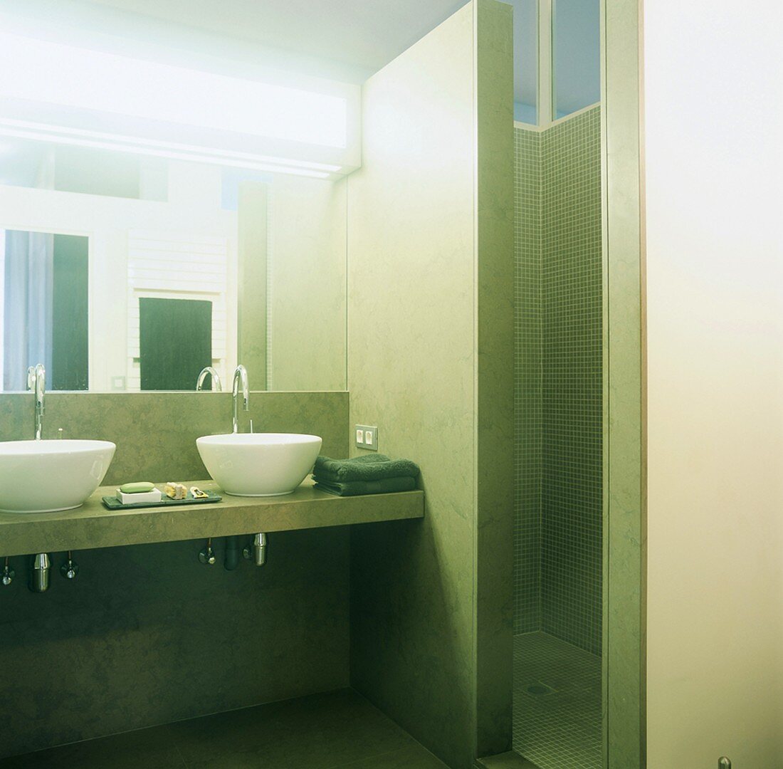 Grün marmoriertes Badezimmer mit weissen Aufsatzbecken und gemauertem Duschraum