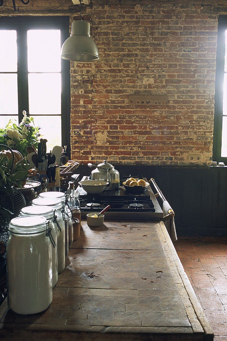 Küche mit rustikaler Arbeitsplatte, Gasherd und Backsteinwand