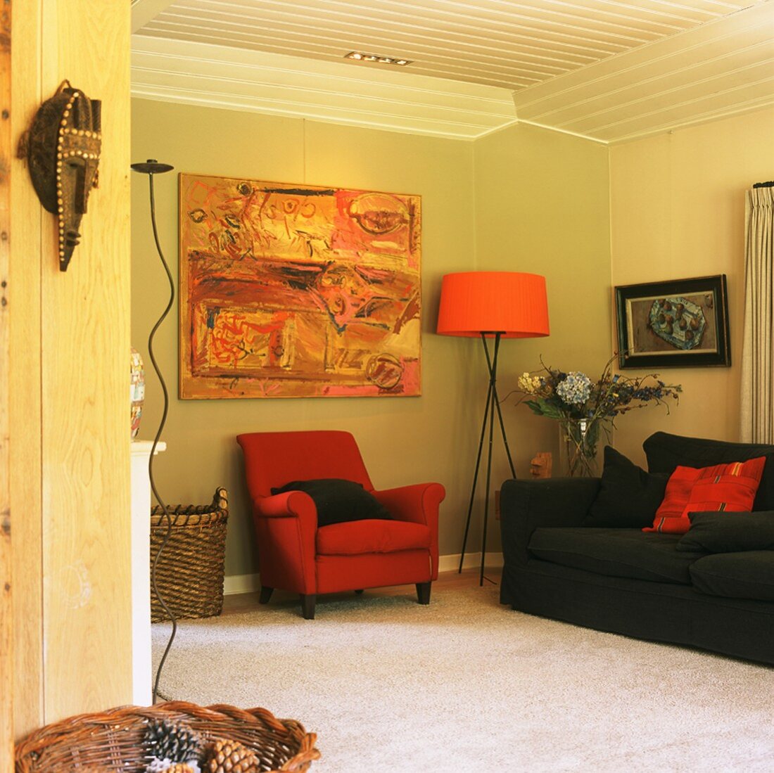 Gemütliche Wohnraumecke mit Polstermöbel, modernem Gemälde und orangefarbener Stehlampe