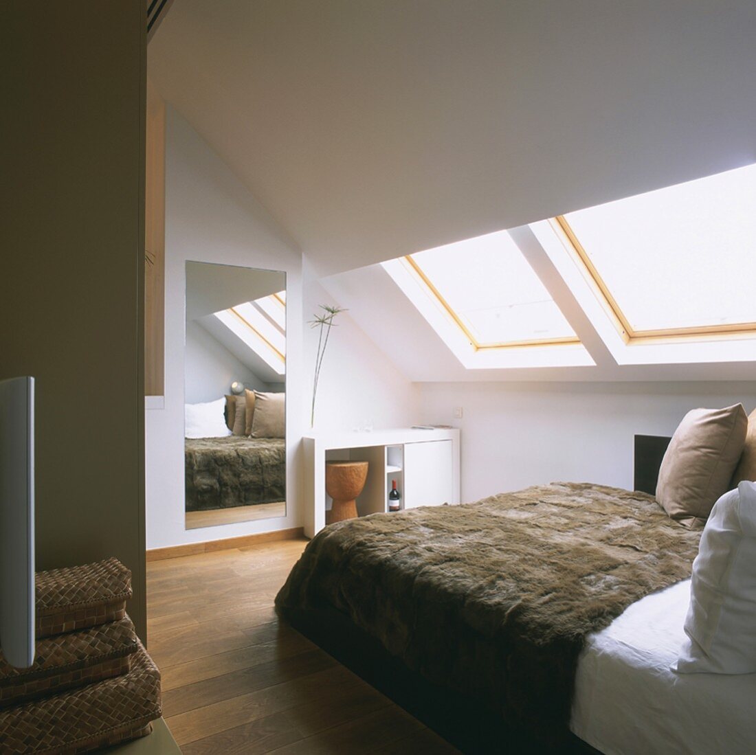 Attic bedroom with large mirror and double bed with fur blanket