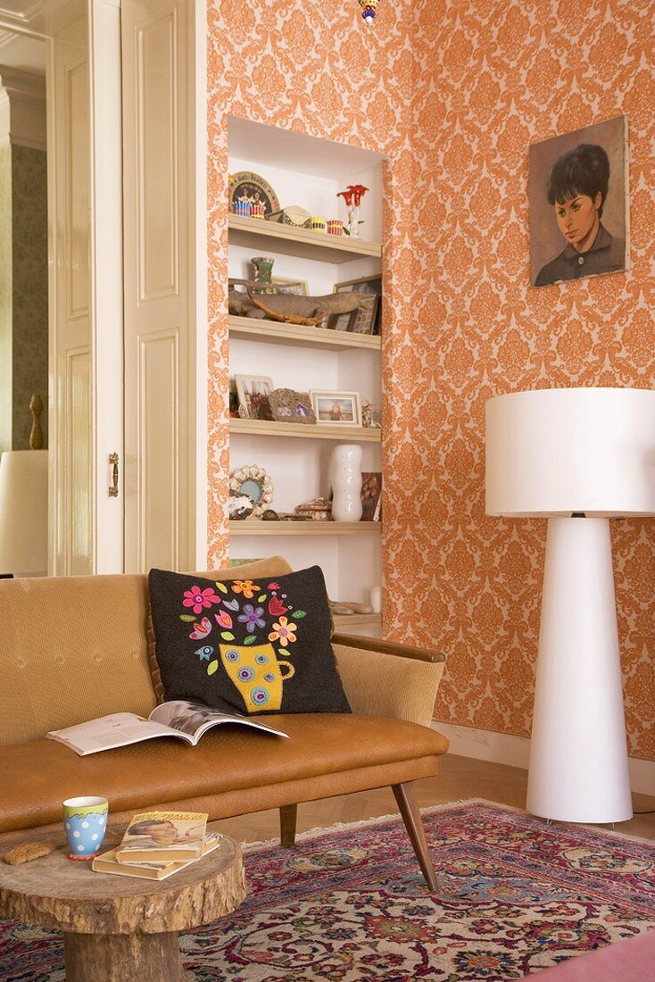 Interior with bookcase in niche, fifties-style couch, rustic coffee table and white standard lamp