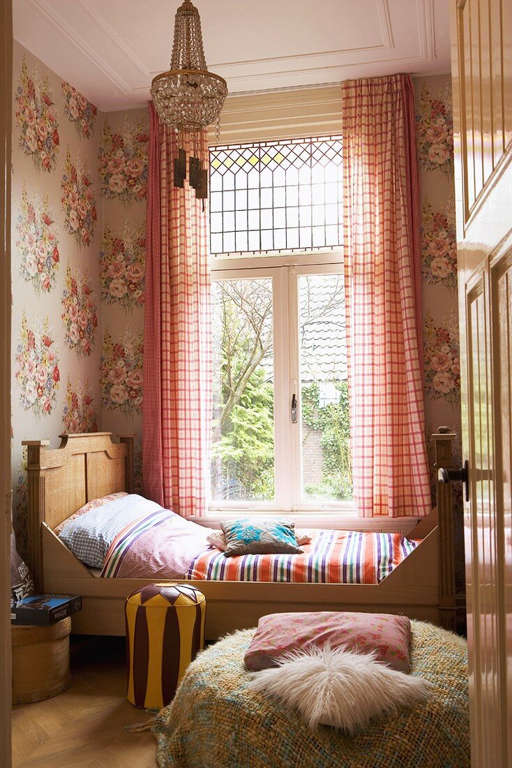 Traditionelles Schlafzimmer mit floraler Wandtapete, antikem Holzbett, Sitzpolster und Fellkissen