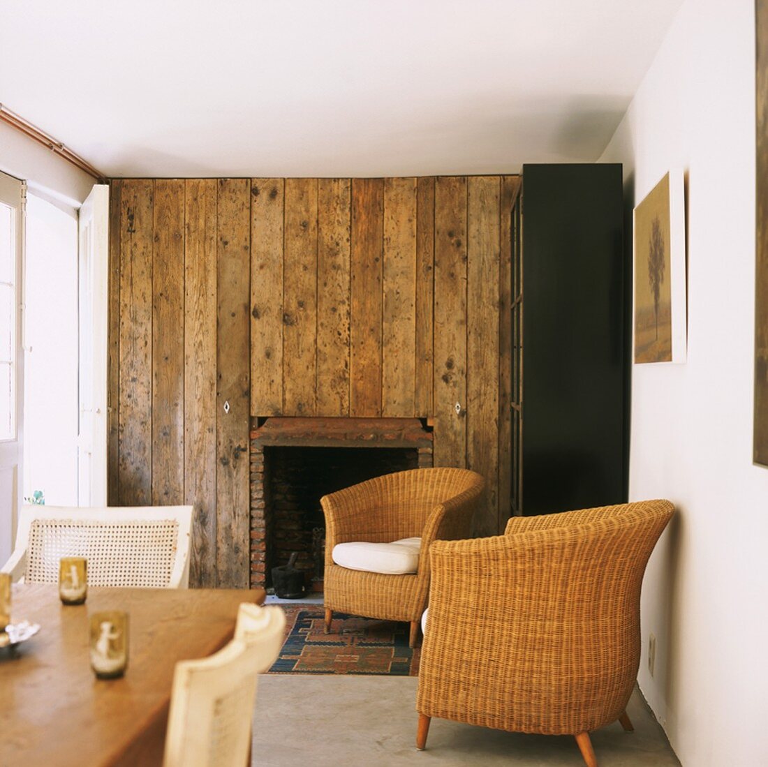 Wohnzimmer mit rustikaler Holzwand und Korbmöbel