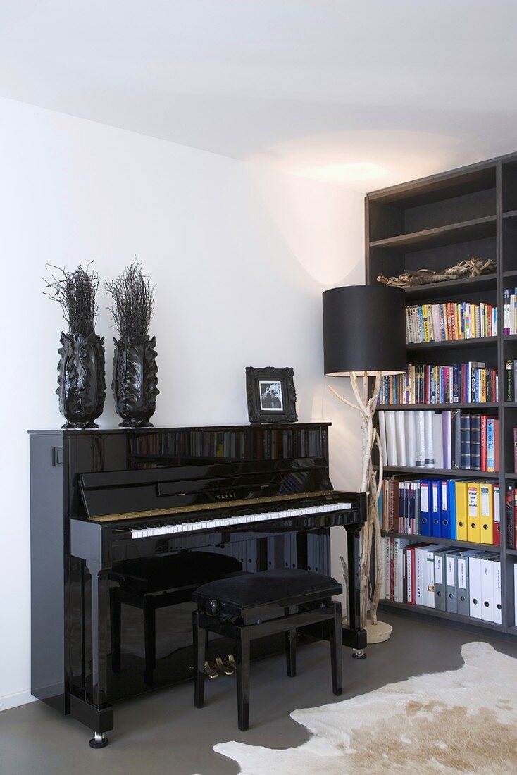 Schwarzglänzendes Klavier in einer Raumecke mit Bücherwand