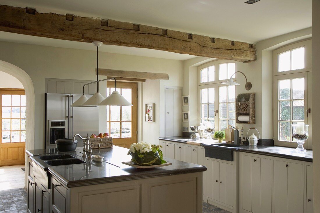 Helle Landhausküche mit Küchenblock, Fenstertüren, Sprossenfenstern, Holzschränken und Küchengeräte mit Edelstahlfront