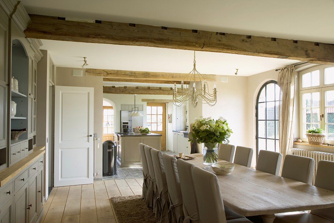 Ess- und Wohnraum mit großer Esstafel, Stühlen und mit Blick in die Küche