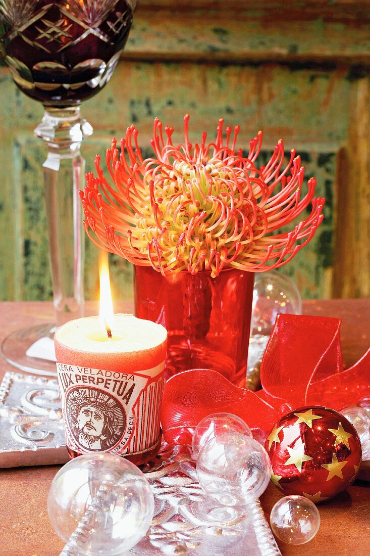 Pincushion flower, candle and Christmas baubles on table