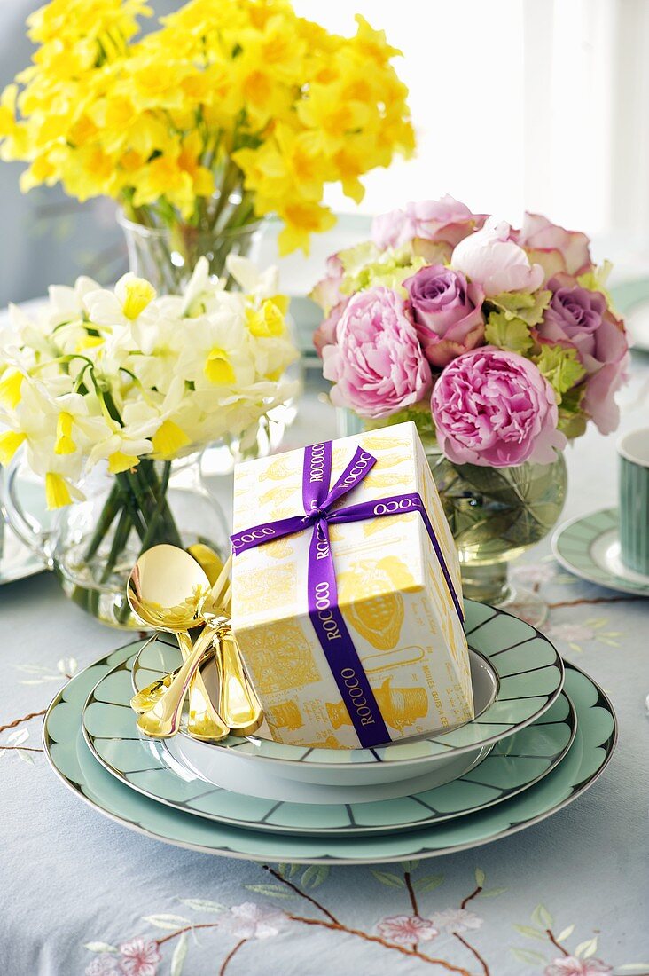 Ostergeschenk und Blumensträusse auf gedecktem Tisch