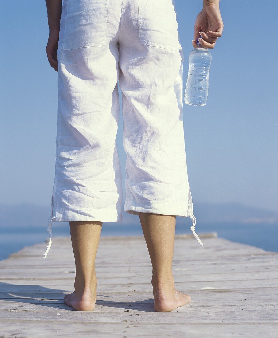 Junge Frau auf einem Steg mit einer Wasserflasche stehend