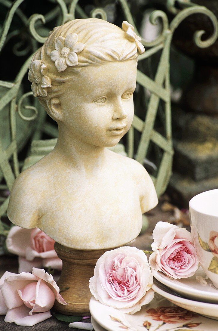 Bust of girl beside crockery and roses