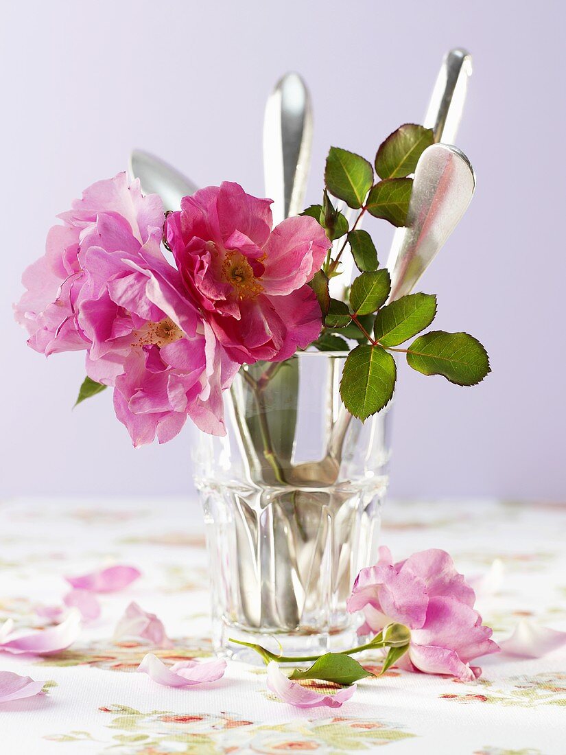 Cutlery and roses in a glass