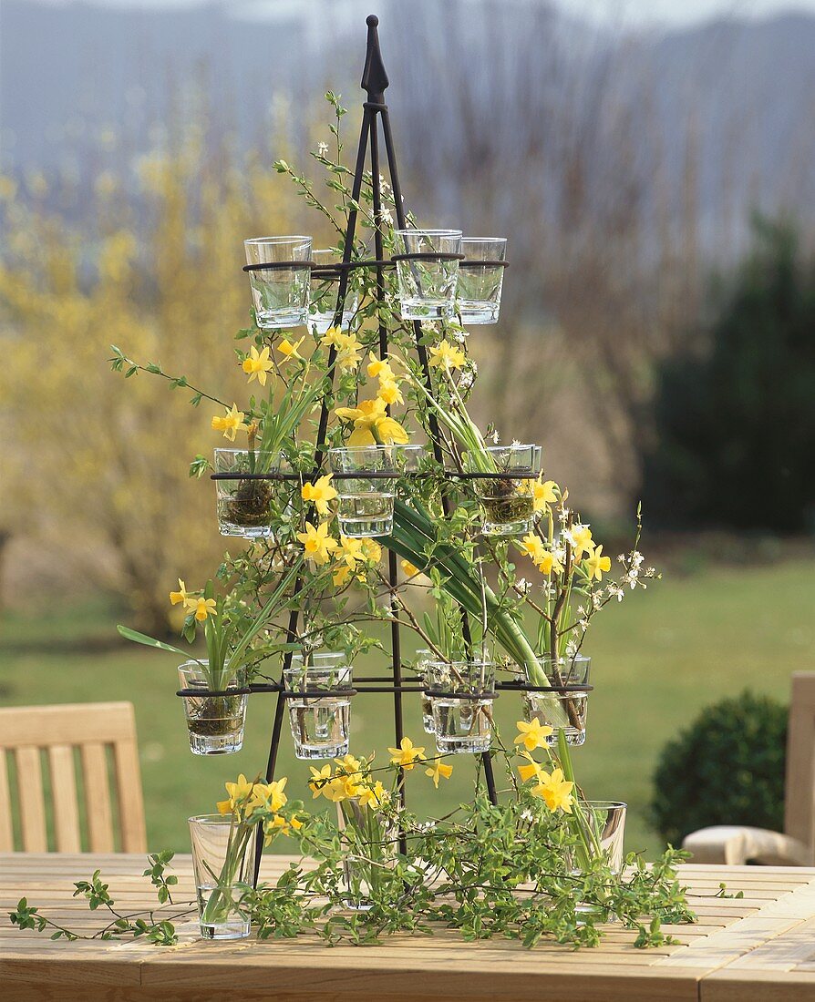 Iron stand with glasses filled with narcissi & twigs