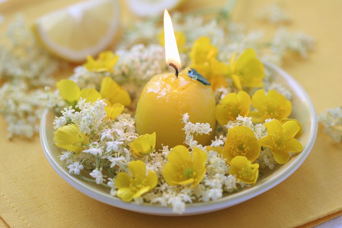 Brennende Kerze mit Blütenkranz